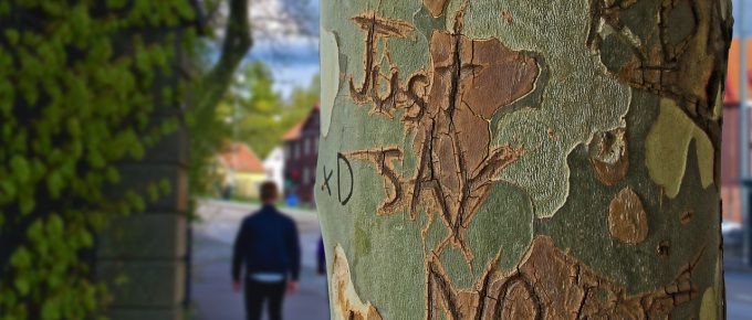 A person setting healthy boundaries while walking down the street next to a tree with graffiti on it.