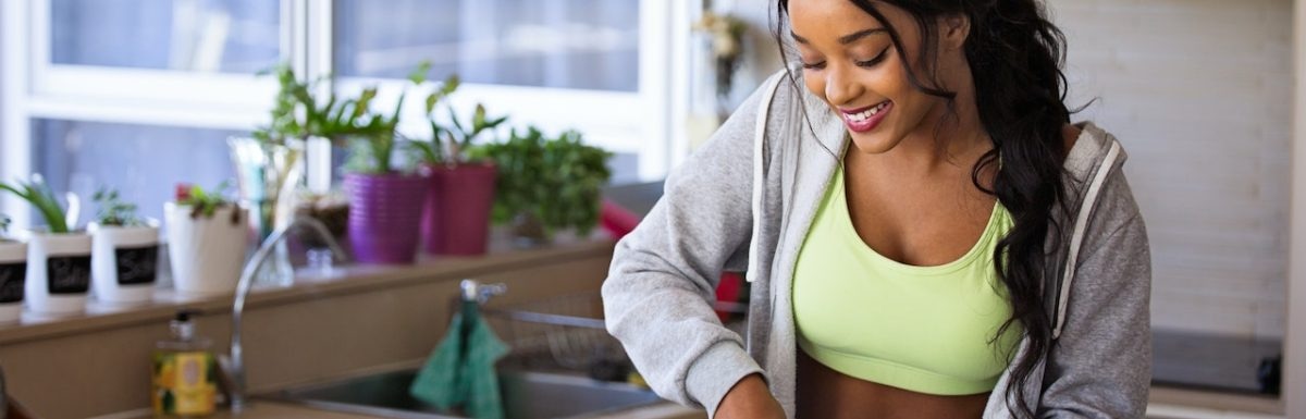 A woman is practicing holistic health tips while preparing food in the kitchen.