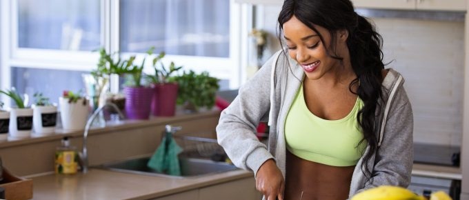 A woman is practicing holistic health tips while preparing food in the kitchen.