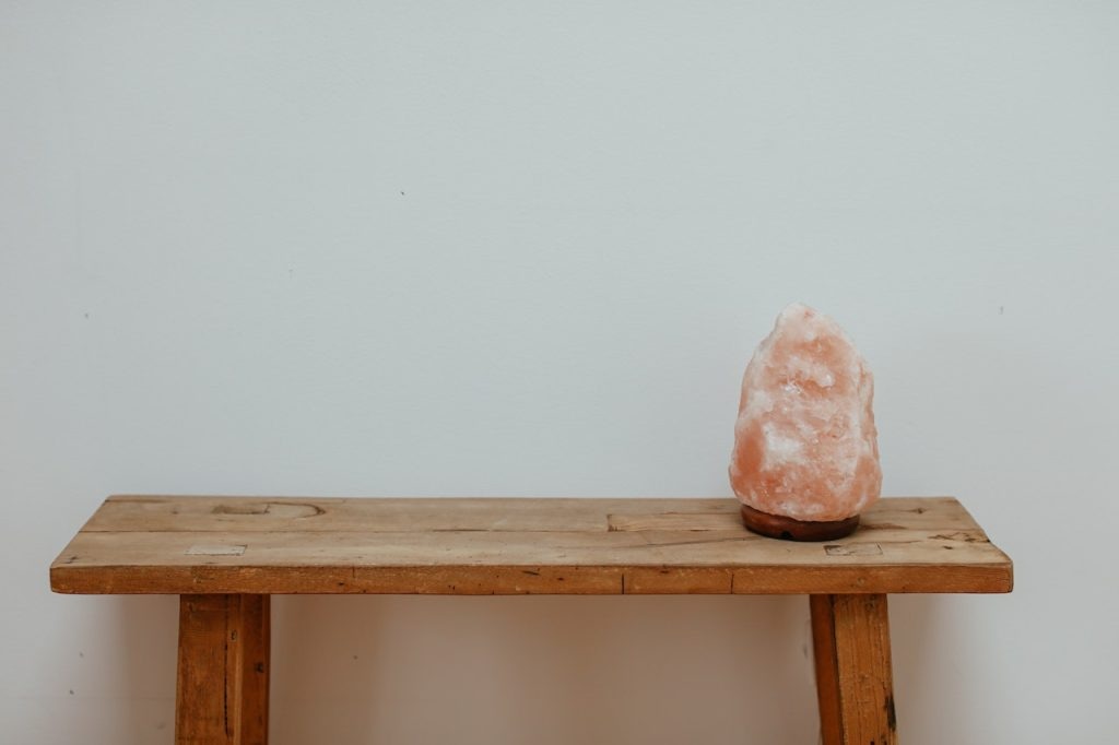 A holistic health tip: Enhance your well-being with a pink salt lamp on a wooden table.