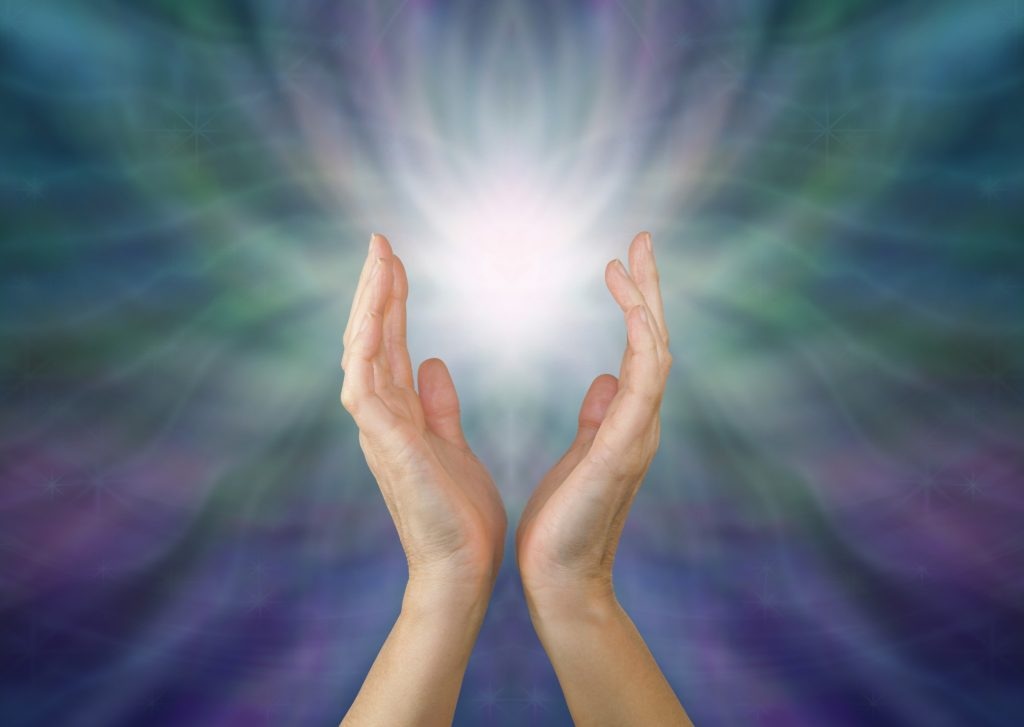 A woman's hands radiating intuitive healing energy.