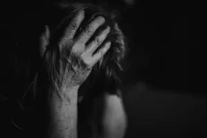 A woman in the midst of trauma, head held in her hands.