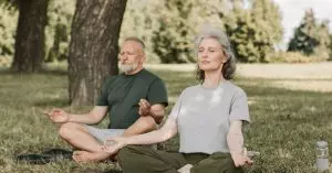 Couple manages their stress by meditating in the park.