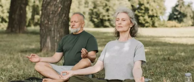 Couple manages their stress by meditating in the park.