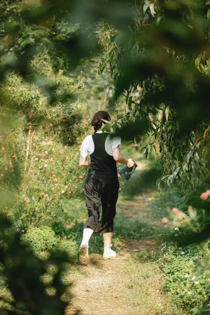 A holistic woman strolling with a frisbee along a path.