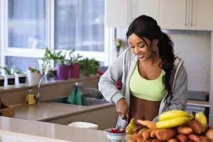 A woman is practicing holistic health tips while preparing food in the kitchen.