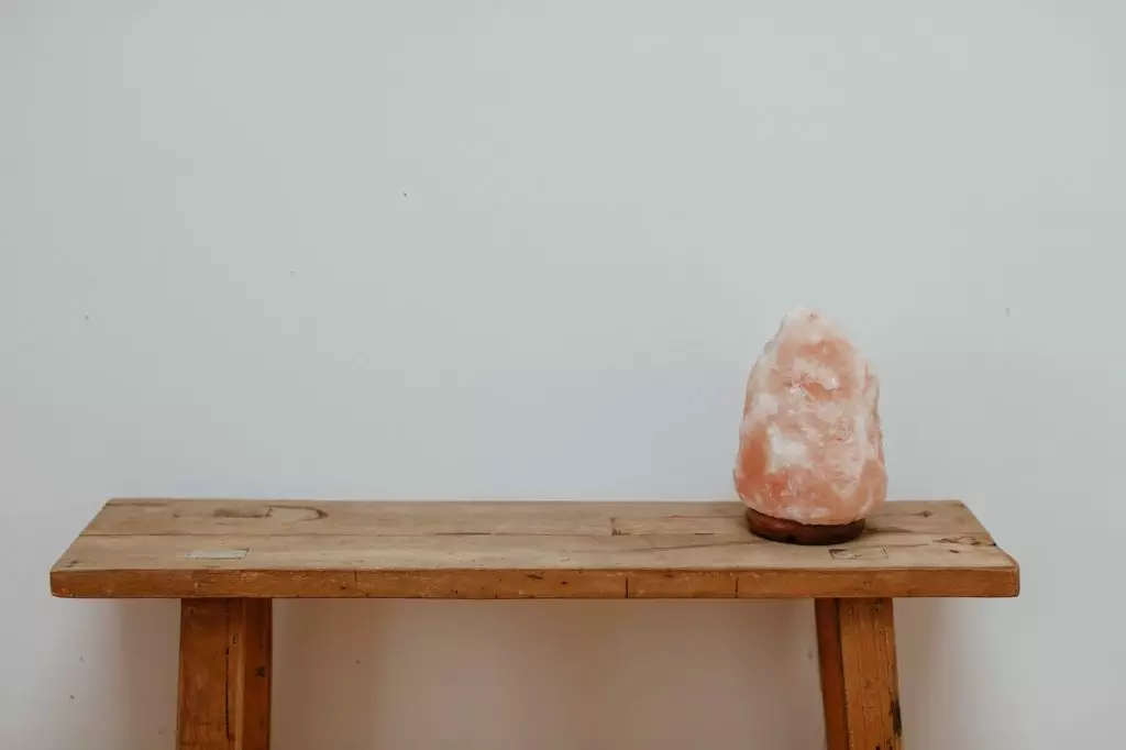 A holistic health tip: Enhance your well-being with a pink salt lamp on a wooden table.