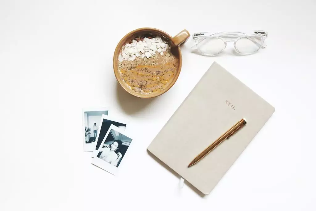 A cup of coffee and a notebook on a white table, featuring holistic health tips.