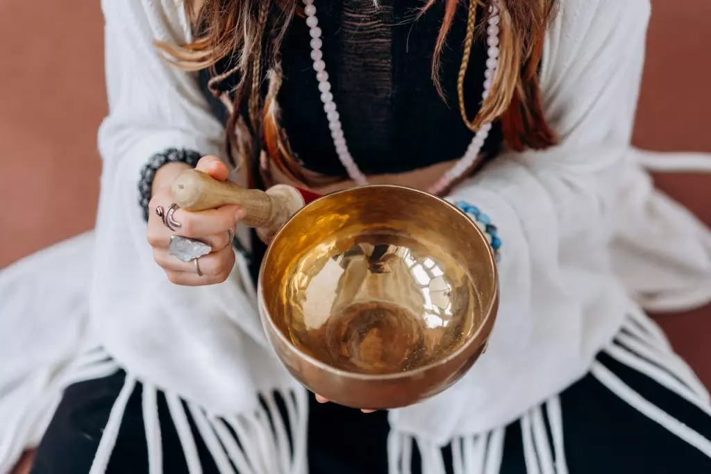 A woman demonstrating sound healing with a singing bowl.