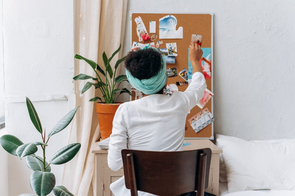 A woman at a desk creating a holistic health tips display with a bulletin board.